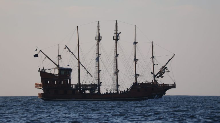 Silhouette of a large sailing ship with multiple masts on the sea.