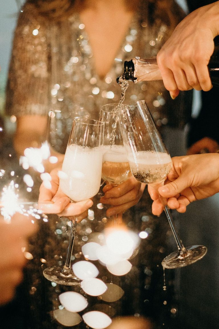 Hands toasting with champagne flutes and sparklers.